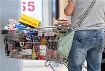Eine Person steht neben einem gefüllten Einkaufswagen.