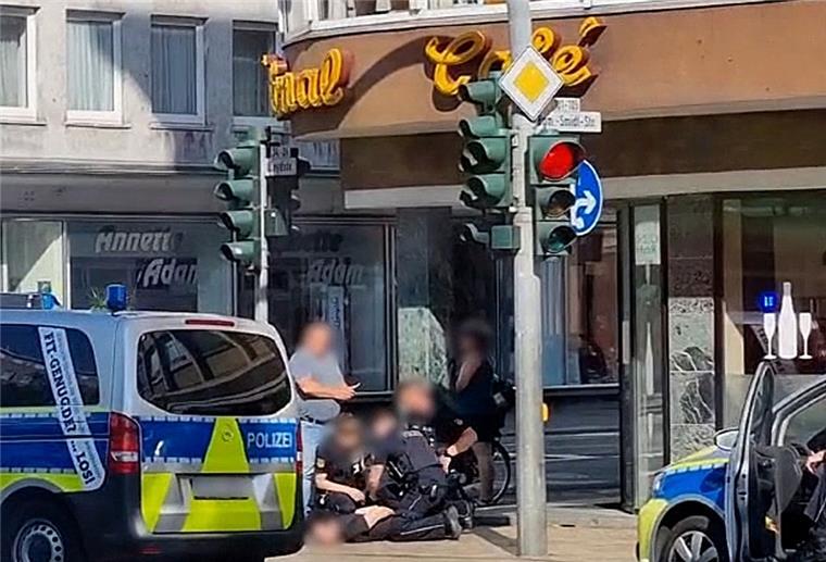 Polizisten nehmen einen Mann fest, der am Boden liegt.