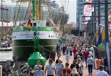 Zahlreiche Menschen laufen auf den Kajen am Neuen Hafen in Bremerhaven an der grün und weiß gestrichenen "Alexander von Humboldt II" vorbei