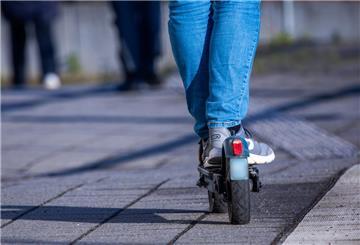 ARCHIV - 17.04.2024, Mecklenburg-Vorpommern, Wismar: Ein Reisender fährt mit seinem E-Scooter über den Bahnsteig. (zu dpa: «E-Scooter-Fahrer stürzt und stirbt») Foto: Jens Büttner/dpa +++ dpa-Bildfunk +++