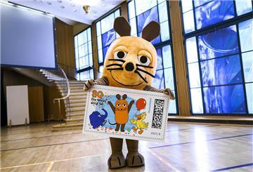 HANDOUT - 24.02.2021, Nordrhein-Westfalen, Köln: Die Hauptdarstellerin der Sendung mit der Maus hält eine überdimensionale Briefmarke mit ihren Darsteller-Kollegen Elefant und Ente in den Händen. Die «Sendung mit der Maus» bekommt eine eigene Briefmarke. Rechtzeitig vor dem 50. Geburtstag der ARD-Sendung erscheint am nächsten Montag (1. März) eine 80-Cent-Sondermarke mit Maus, Elefant und Ente, wie der WDR am Mittwoch in Köln mitteilte. Foto: Ben Knabe/WDR/dpa - ACHTUNG: Nur zur redaktionellen V