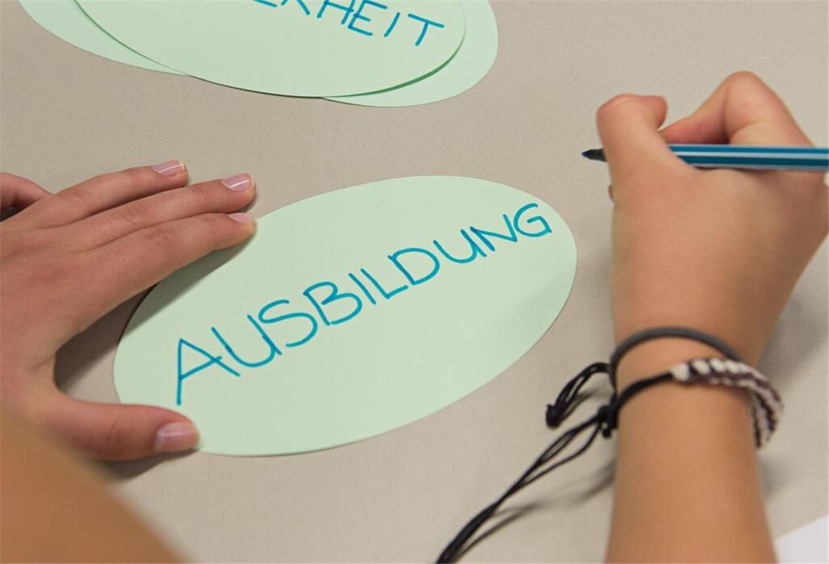 Ein Zettel mit der Aufschrift "Ausbildung" liegt in einem Klassenzimmer auf einem Tisch