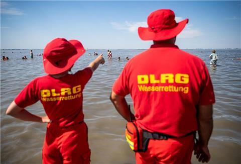 Mitglieder der DLRG (Deutsche Lebens-Rettungs-Gesellschaft) stehen am Strand von Dangast.