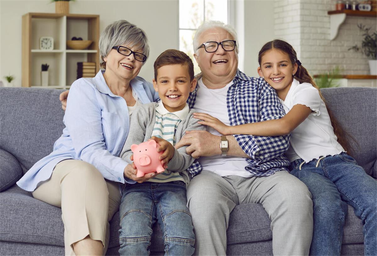 2500 Euro Rente für jeden! Neues Merz-Vorhaben startet schon 2026 Großeltern sitzen mit ihren Enkeln auf einem Sofa und halten ein Sparschwein in der Hand.