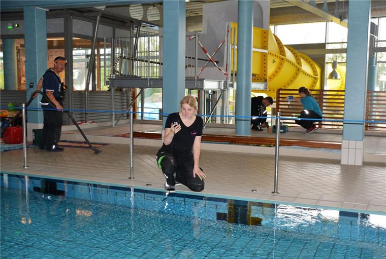 Badesaison startet in der Moor-Therme – Rutsche noch nicht fertig 27,7 Grad sollen es sein: Leonie Sticht prüft die Wassertemperatur im Sportbecken. Nando Gutschera, Oliver Webb und Stephanie Schories reinigen unter dem künftigen Rutschen-Startbecken.