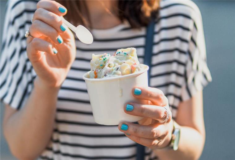 Sommer-Schock auf Norderney: So viel kostet eine Kugel Eis jetzt Frau hält Eisbecher in der Hand.