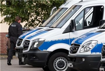 Drei Polizeiautos parken und ein Beamter läuft vorbei. 