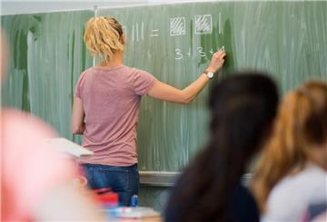 Eine junge Lehrerin schreibt an einer Schultafel.