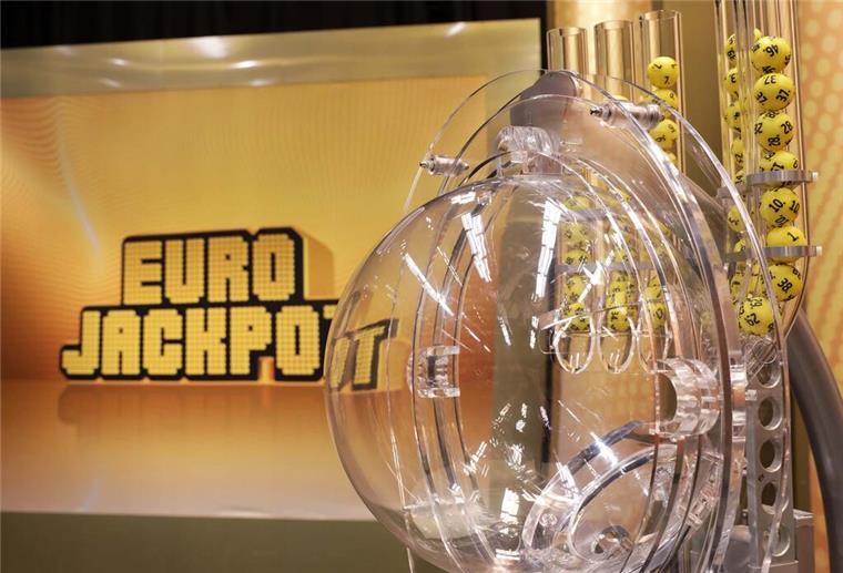 Die Lostrommel des Eurojackpots steht im Vordergrund. Im Hintergrund steht der Schriftzug Eurojackpot.