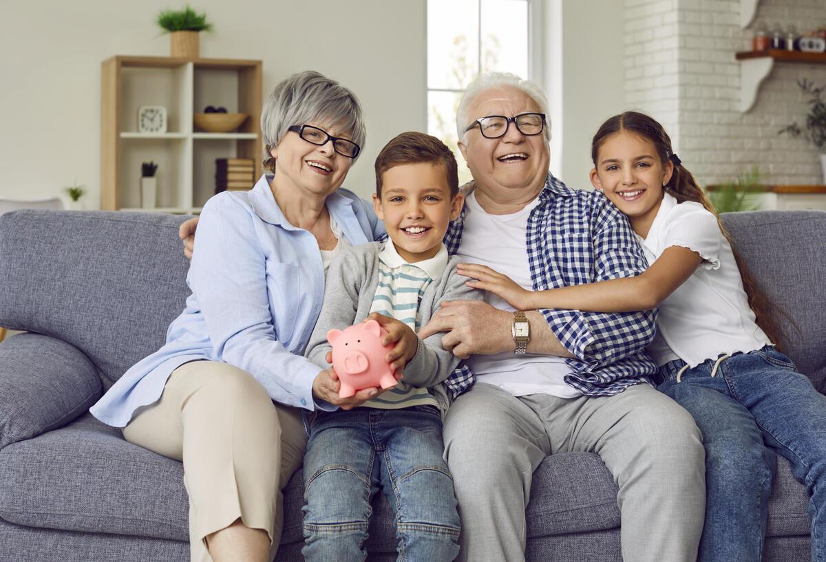 Eine Familie auf dem Sofa mit einem Sparschwein in der Hand.