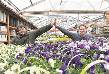 Zwei Männer klatschen hinter vielen Blumen ein