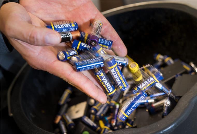 Batterien liegen auf einer Hand und in einem Behälter. Ab August wird das Entsorgen von Batterien transparenter. Wir erklären die neue Müll-Regel.