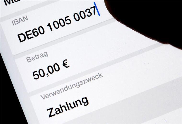  Eine Frau nutzt auf ihrem Smartphone eine App, um im Online-Banking eine SEPA-Überweisung zu veranlassen (gestellte Szene). 