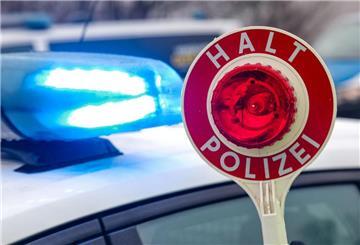  Ein Polizist hält eine Polizeikelle für eine Kontrolle auf einem Parkplatz an der Autobahn. 