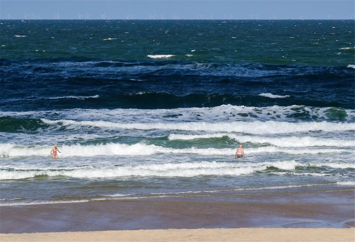 Badegefahr durch Vibrionen: Diese Bakterien werden bei Hitze lebensgefährlich Strandbesuchende stehen bei sommerlichem Wetter in der Nordsee-Brandung am Strand in Westerland.