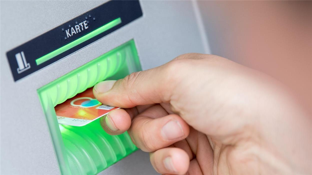 Eine Person steckt ihre Bankkarte in einen Geldautomaten.