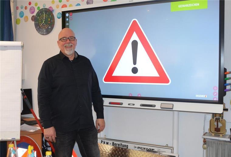 Fahrlehrer steht vor einer Leinwand mit Verkehrsschild.