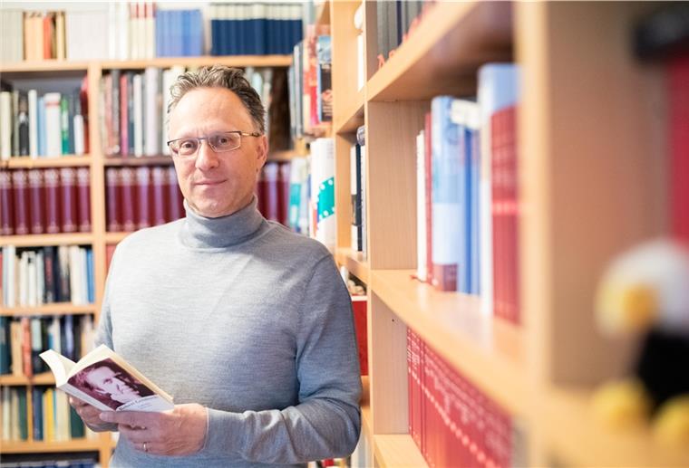 Sebastian Loskant mit Gedichtband von Robert Gernhardt vor Bücherwand.
