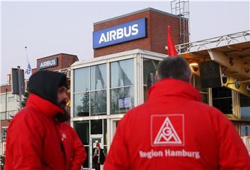 Mitglieder der IG Metall stehen am 02.12.2021 mit Transparenten und Schildern vor einem Werkstor von Airbus in Hamburg-Finke