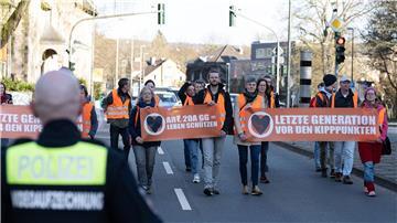 Aktivisten der Bewegung „Letzte Generation“ gehen mit Plakaten bei einem friedlichen Protestmarsch über eine Hauptverkehrsstraße.