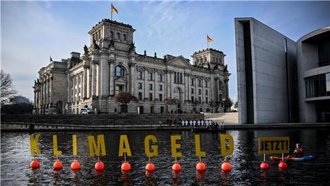 Aktivisten paddeln in der Spree und zeigen Plakate mit der Aufschrift „Klimageld Jetzt!“.
