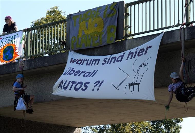 Klima-Aktivisten seilen sich von einer Brücke über der A27 ab und bringen Plakate an.