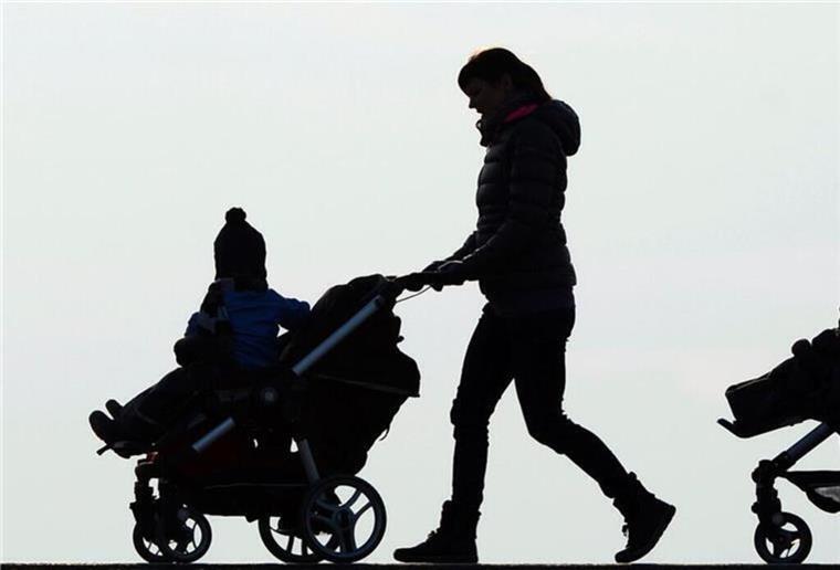 Eine Mutter schiebt einen Kinderwagen. 