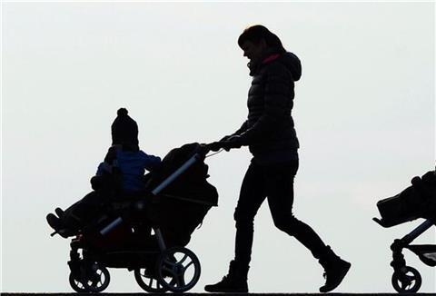 Eine Mutter schiebt einen Kinderwagen. 