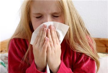 Maedchen, 10 Jahre alt, liegt krank, mit Grippe, zuhause im Bett, im Kinderzimmer. Hustet, hat Schnupfen.
