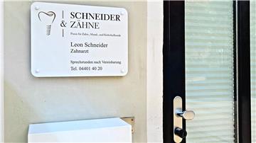 Ein Schild eines Arztes hängt neben einer Tür.