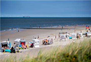 Touristen sitzen bei sonnigem Wetter in Strandkörben am Strand