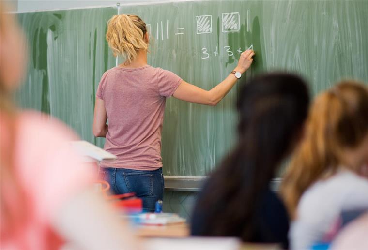 Eine junge Lehrerin schreibt in einer Schule in Niedersachsen an eine Schultafel.
