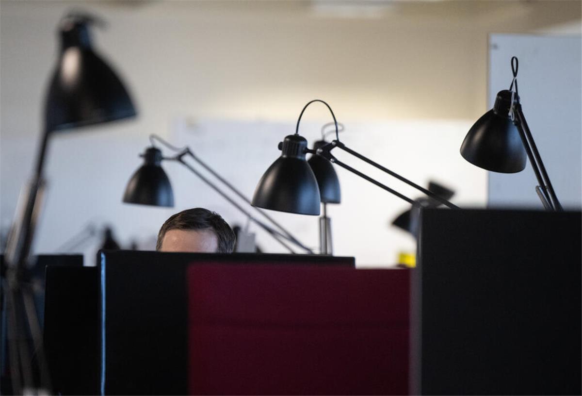 Ein Mann sitzt an einem Büro Schreibtisch. Alle warten: Hängt das IT-System, müssen Beschäftigte oft ihre Arbeit pausieren. Auf ihre Arbeitszeit hat das in der Regel keinen Einfluss. 
