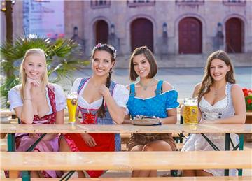 Vier junge Frauen in Trachten sitzen auf einer Bierbank.