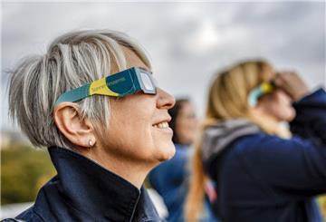 ARCHIV - 24.10.2022, Hamburg: Eine Besucherin des Hamburger Planetariums betrachtet von der Aussichtsterasse aus mit Schutzbrille eine partielle Sonnenfinsternis. (zu dpa: «Ein Teil der Sonne verschwindet») Foto: Axel Heimken/dpa +++ dpa-Bildfunk +++
