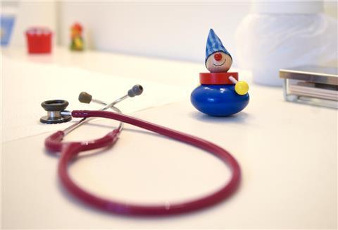 Ein Stethoskop und Kinderspielzeug liegen in einer Kinderarztpraxis auf einem Tisch.