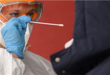Ein Mitarbeiter nimmt einen Abstrich von einer Patientin für einen PCR-Test auf das Coronavirus vor einer Arztpraxis.