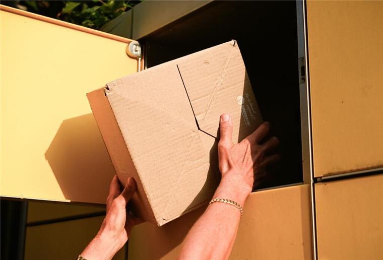 Eine Person holt ein Paket aus einer Packstation. 