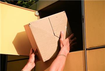 Eine Person holt ein Paket aus einer Packstation. 