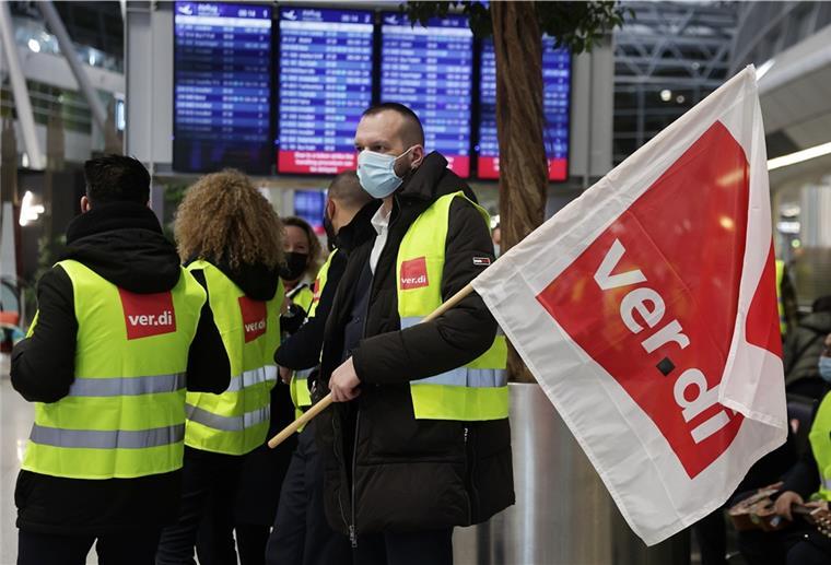 Mehrere Protestanten in gelben Warnwesten stehen am Flughafen.