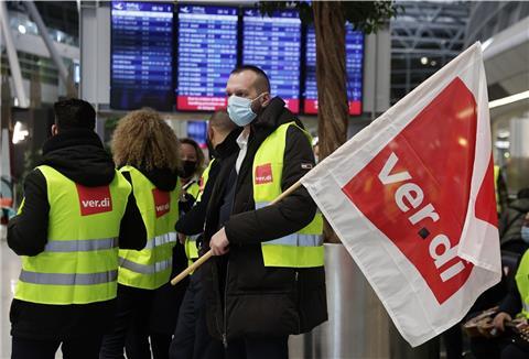 Mehrere Protestanten in gelben Warnwesten stehen am Flughafen.