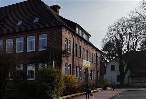 Ein Kind geht zum Eingang einer Schule.