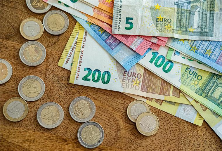 Geldscheine und Münzen liegen auf einem Tisch. An der Kasse wird's entspannter: Die Inflation ist gesunken – aber nicht in allen Bereichen. Dienstleistungen bleiben teuer, und neue Preisrisiken sind nicht vom Tisch.