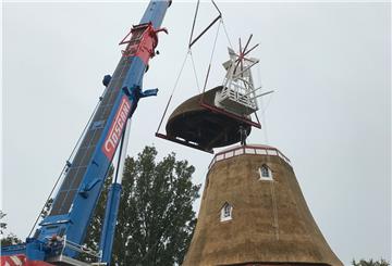 An einer Kette zieht der Dachdecker die sanierte Reetdach-Haube der Beerster Mühle an ihren ursprünglichen Platz.