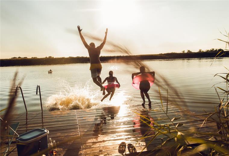 Hitze im Sommer – So wappnet man sich am besten Menschen springen in einen See