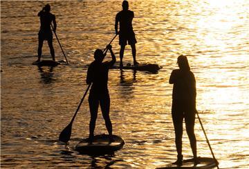 Mehrere Stand-Up-Paddler sind auf einem See unterwegs. 