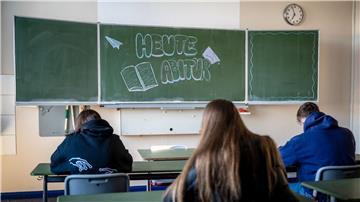 Schüler sitzen vor einer Tafel mit der Aufschrift "Heute Abitur"