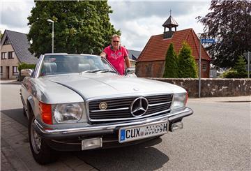 Ein Mann neben einem Oldtimer.