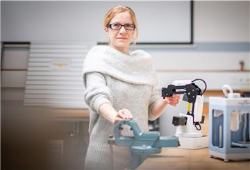 Eine Frau zeigt einen Leichtroboter. 