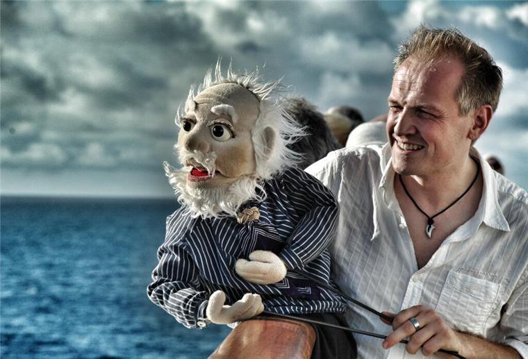 Ein Mann und eine Handpuppe in Form eines Kapitäns.